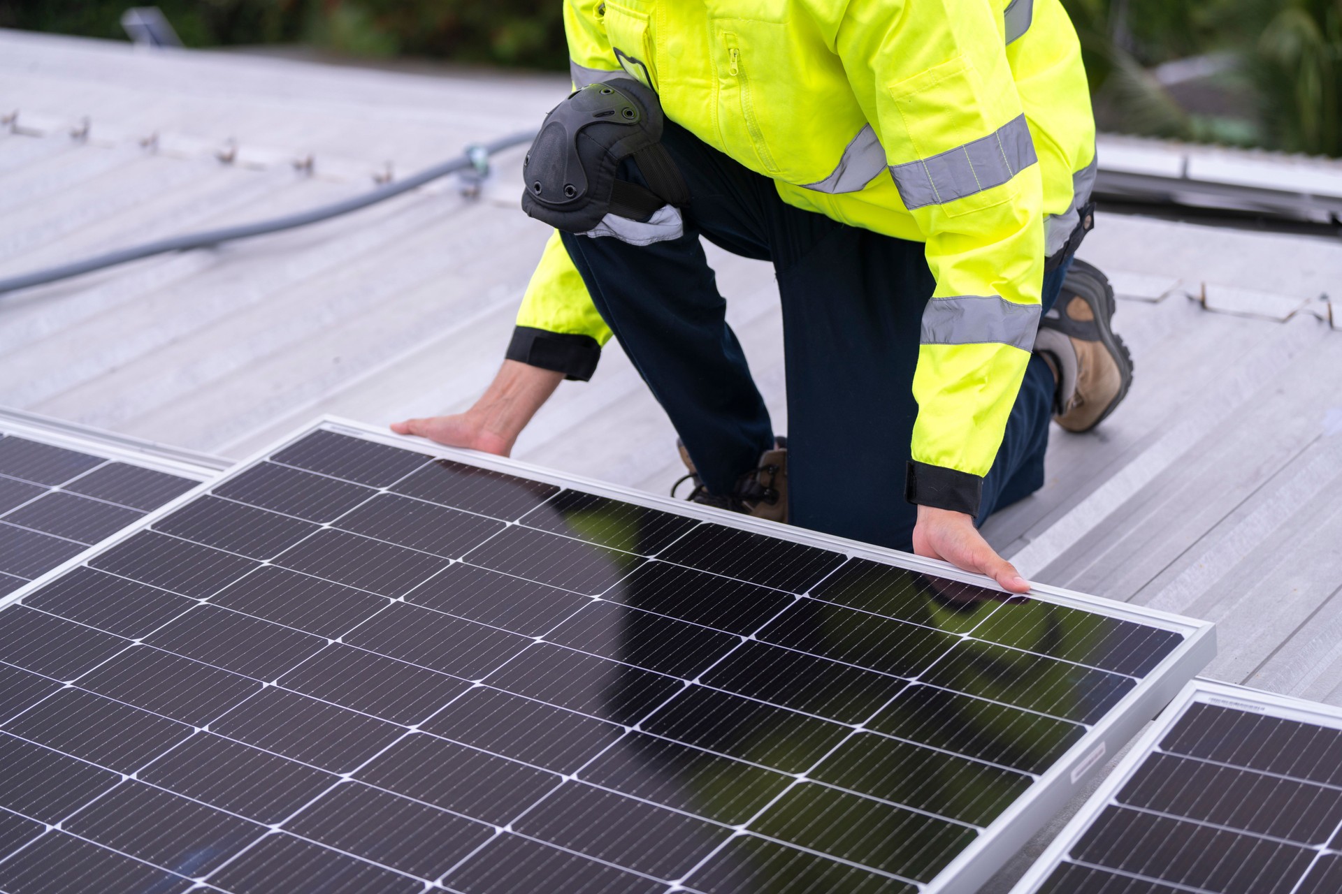technician lifting a photovoltaic panel during installation, showcasing renewable energy advancement. Dressed in safety gear, reflecting a focus on green energy solutions and sustainable development.